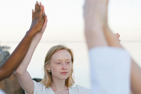 A diverse group of individuals engaged in meditation and mindfulness by the ocean.